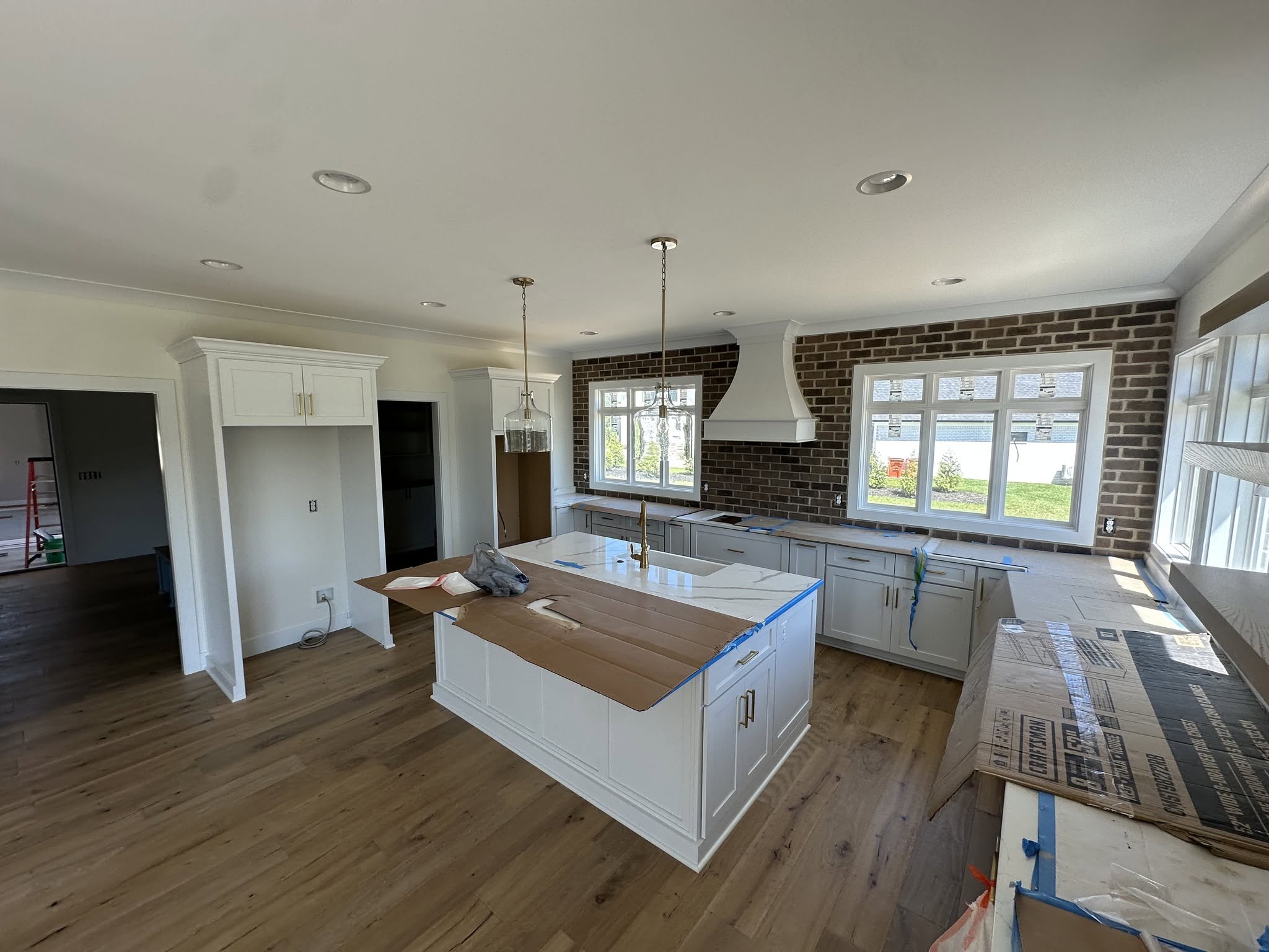 Bright custom kitchen with white cabinetry, a large island, and brick accent wall